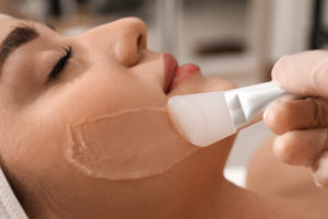 Young woman during face peeling procedure in salon | AIYANA Aesthetics